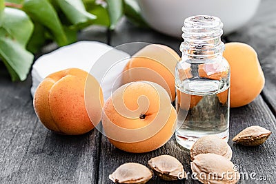 A bottle of apricot oil with apricot seeds and ripe apricots on a wooden table Stock Photo