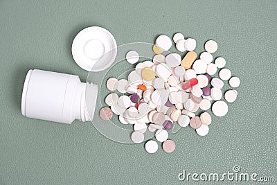 Bottle and a bunch of expired pills green background Stock Photo