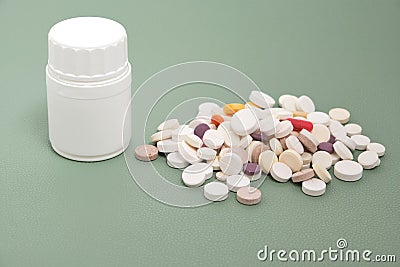 Bottle and a bunch of expired pills green background Stock Photo