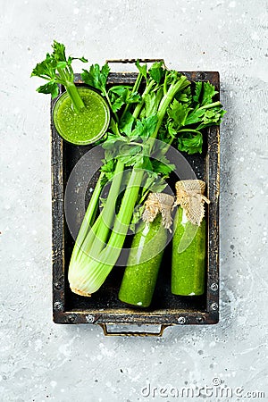 A bottle of celery juice in a box on a stone background. Vegetarian drink. A stalk of fresh celery. Stock Photo