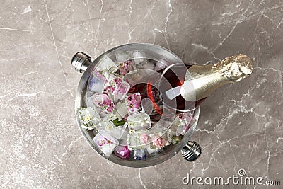 Bottle of champagne with floral ice cubes in bucket on table Stock Photo