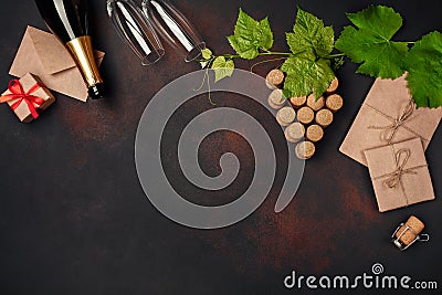 Bottle of champagne, gape bunch of cork with leaves, two wineglass, envelope and gift box on rusty background. Stock Photo