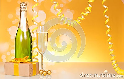 A bottle of champagne, a New Year`s gift on a yellow shimmering Stock Photo