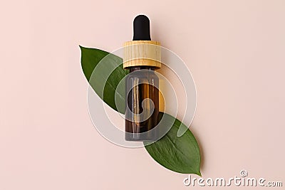 Bottle of cosmetic from the brown transparent glass with natuarl oil in it.Green leafs under it.Flat lay style.Organic concept Stock Photo