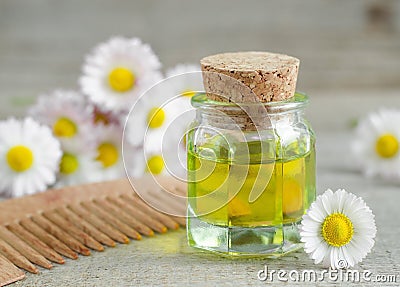 Bottle of cosmetic chamomile oil and wooden hair comb Stock Photo