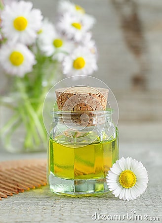 Bottle of cosmetic chamomile oil and wooden hair comb Stock Photo