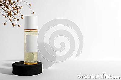 Bottle of cosmetic product, dried flowers and round podiums on white background, space for text Stock Photo