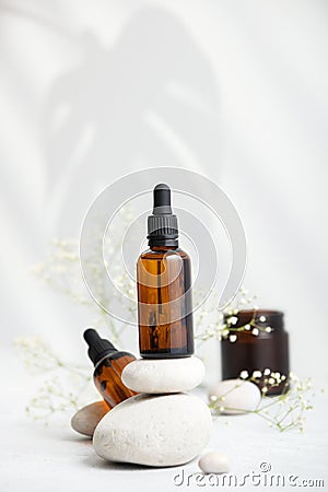 Bottle of dark amber glass with essential oil on stack of natural stones, copy space Stock Photo