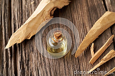 A bottle of essential oil with pieces of white sandalwood on a table Stock Photo