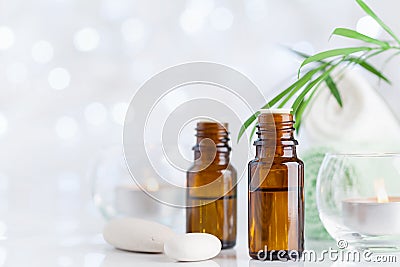 Bottle with essential oil, towel and candles on white table. Spa, aromatherapy, wellness, beauty background. Stock Photo