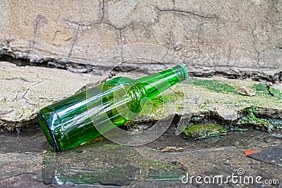 A bottle of expired beer thrown into a puddle Stock Photo