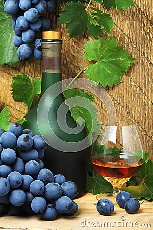 Bottle, glass of cognac and bunch of grapes Stock Photo