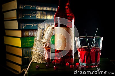 Bottle and glass with craft cranberry alchol drink on background with books Stock Photo