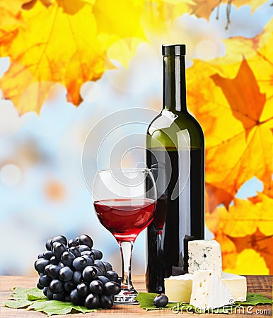 Bottle, glass of red wine and assorted cheeses Stock Photo