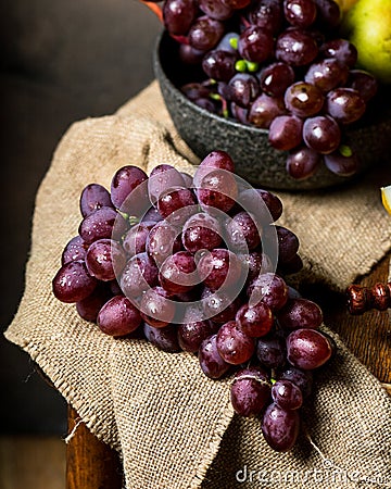 Bottle and glass of red wine, grape and cork on chair. Melon, piece of melon. Pink grape, pear. Still life of food. Dark Stock Photo