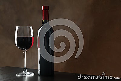 Bottle and glass with wine against brown background Stock Photo