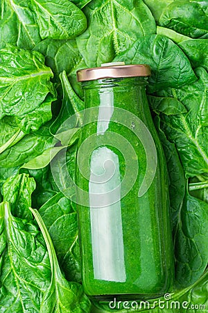 Bottle with Green Fresh Raw Smoothie from Leafy Greens Vegetables Fruits Apples Bananas Kiwi Zucchini on Spinach Leaves Background Stock Photo