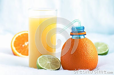 A bottle made of natural orange and a glass of freshly squeezed orange juice surrounded by slices of tropical orange and lime Stock Photo