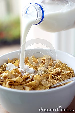 A bottle of milk being poured into a bowl of cereal. Conceptual image shot Stock Photo
