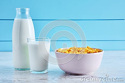 Bottle of milk, bowl of cereal corn flakes and a glass full of milk on a wooden table Stock Photo