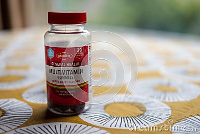 A bottle of mixed berry flavor multivitamin gummies on a table with a brightly colored cloth Editorial Stock Photo
