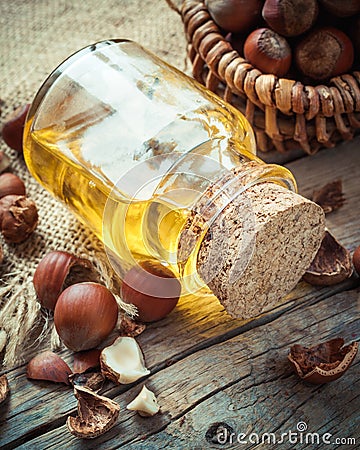 Bottle of nut oil and basket with filberts on table Stock Photo