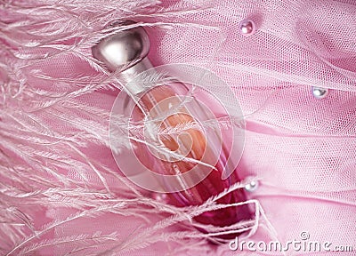 A bottle of perfume on pink veil with ostrich feathers and pearls. Perfumes, cosmetics, a collection of fragrances. Stock Photo