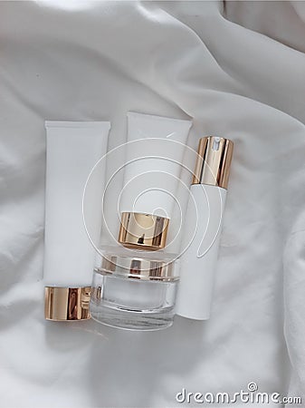 A bottle of perfume and white body lotion plastic packaging and golden lid Stock Photo