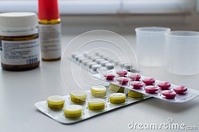 Bottle pills, measuring cup and medicine capsule on table Stock Photo