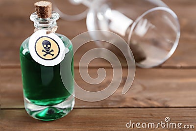 Bottle of poison and partially emptied glass on wooden table Stock Photo