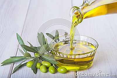 Bottle pouring virgin extra olive oil in a bowl Stock Photo