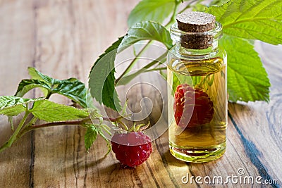 A bottle of raspberry seed oil with fresh raspberries Stock Photo