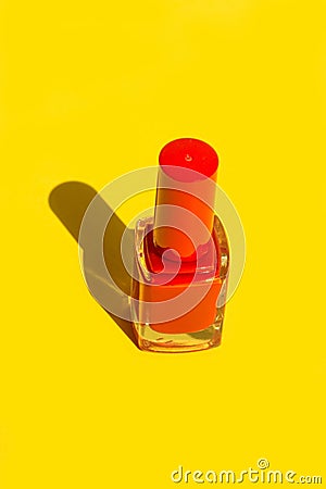 Bottle with red crimson nail polish on solid yellow background. Bright sunlight strong shadows. Creative minimalist funky style Stock Photo