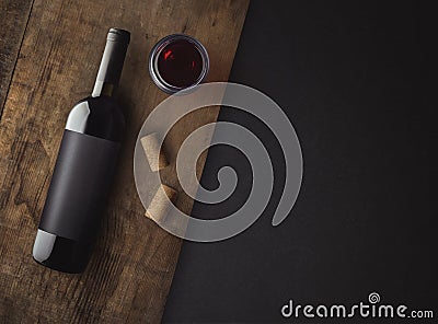 Bottle of red wine with label on old board. Glass of wine and cork. Wine bottle mockup. Stock Photo