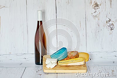 Bottle of red wine and variation of cheese on wooden board Stock Photo