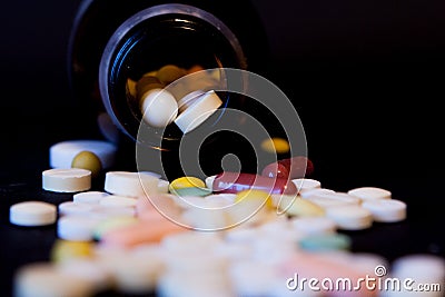 A bottle of spilled pills on black background.Levitating tablets. Tablets on a dark background that are falling. Tablets. Medicine Stock Photo