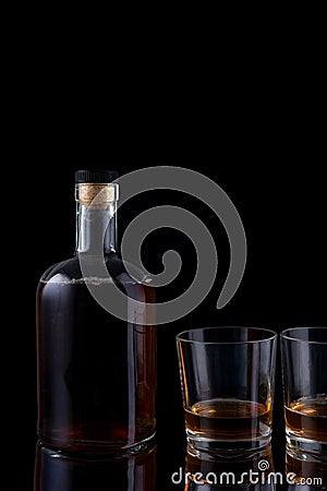 bottle of strong alcohol brandy with glasses on black background Stock Photo