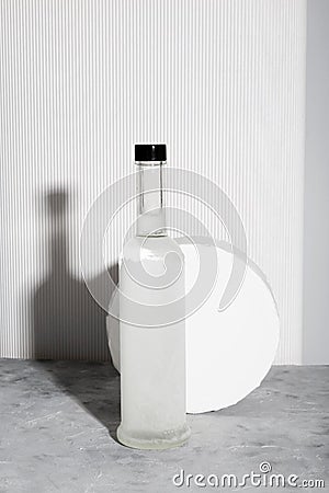 Bottle of vodka and white stand. Shadows and sunlight trends Stock Photo