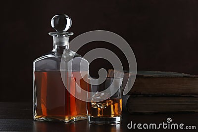 Bottle of whiskey with glass and old books on brown background Stock Photo