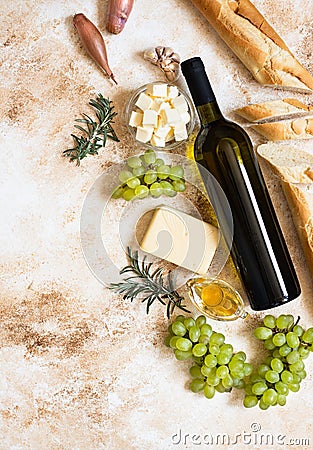 A bottle of white wine, grapes, cheese, butter, honey, baguette, shallot and rosemary Stock Photo