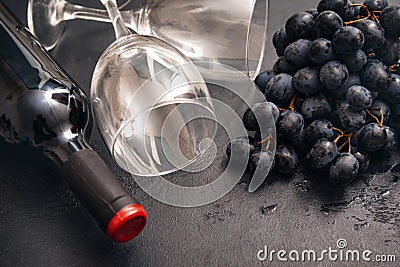 1 bottle of wine, bunch of dark grapes, 2 empty glass, rose on a dark Stock Photo