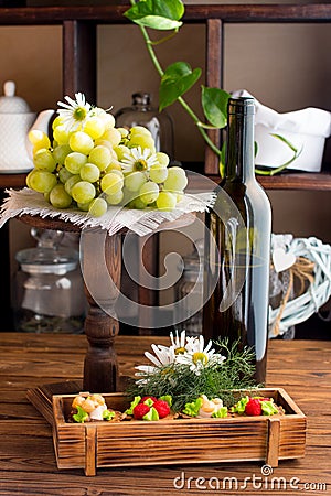 A bottle of wine, cakes and a branch of grapes on display. Stock Photo