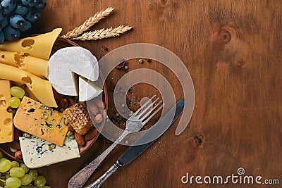 A bottle of wine, and a large assortment of cheeses, honey, nuts and spices, on a wooden table. Top view. Stock Photo
