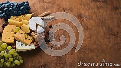 A bottle of wine, and a large assortment of cheeses, honey, nuts and spices, on a wooden table. Top view. Stock Photo