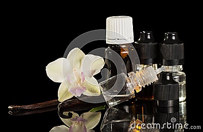 Bottles of aromatic liquid for vaping, vanilla pods and Orchid flower isolated on black Stock Photo