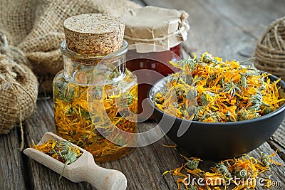 Bottles of calendula infusion, healthy marigold flowers in bowl and calendula salve on wooden table. Herbal medicine Stock Photo