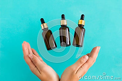 Bottles with cosmetic products levitate over women`s hands on a blue background Stock Photo