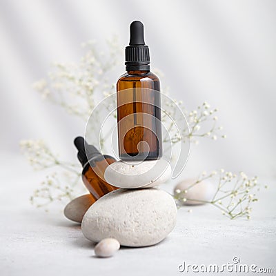 Bottles of dark amber glass with essential oil on stack of natural stones Stock Photo