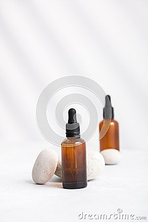 Bottles of dark amber glass with essential oil on stack of natural stones, copy space Stock Photo