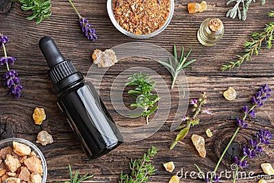 Bottles of essential oil with frankincense, tulsi, mountain savory and other herbs on wood Stock Photo